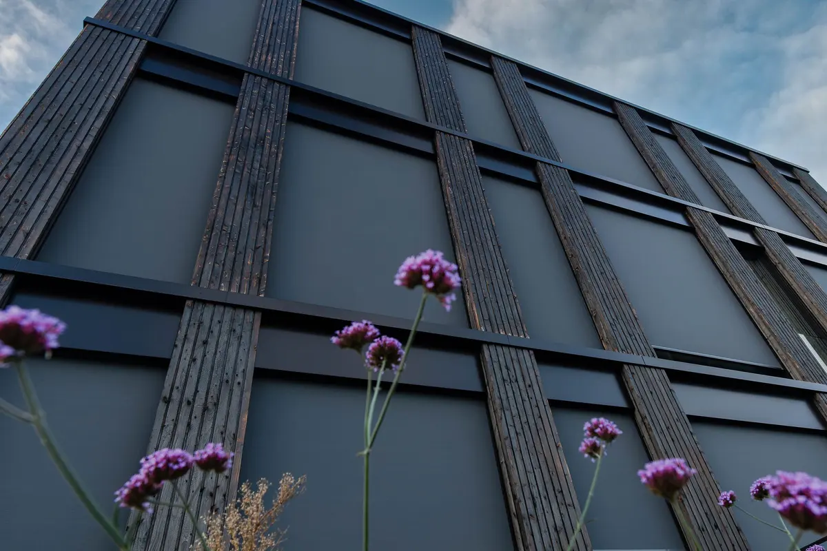 Holzfassade des neuen Bürogebäudes mit Blumen